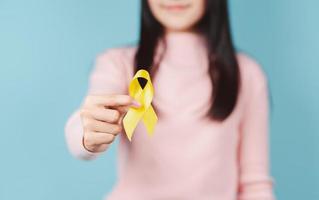 happy woman holding yellow ribbon, september, suicide prevention day, childhood, sarcoma, bone and bladder cancer Awareness month, health care support people and world cancer day concept photo