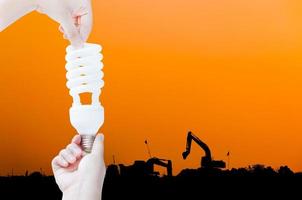 Energy saving concept, Woman hand holding light bulb on industry Landscape background,Ideas light bulb in the hand photo