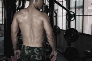 Sexy body of muscular young soldier Asian man in gym. Concept of health care, exercise fitness, Strong muscle mass, body enhancement, fat reduction for men's health supplement product presentation. photo