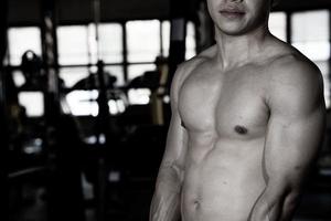 Sexy body of muscular young soldier Asian man in gym. Concept of health care, exercise fitness, Strong muscle mass, body enhancement, fat reduction for men's health supplement product presentation. photo