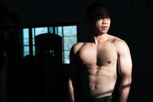 Sexy body of muscular young soldier Asian man in gym. Concept of health care, exercise fitness, Strong muscle mass, body enhancement, fat reduction for men's health supplement product presentation. photo