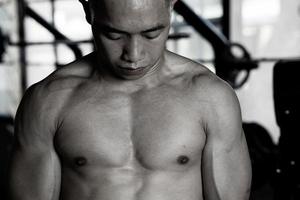 Sexy body of muscular young soldier Asian man in gym. Concept of health care, exercise fitness, Strong muscle mass, body enhancement, fat reduction for men's health supplement product presentation. photo