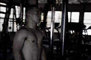 Sexy body of muscular young soldier Asian man in gym. Concept of health care, exercise fitness, Strong muscle mass, body enhancement, fat reduction for men's health supplement product presentation. photo