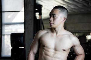 Sexy body of muscular young soldier Asian man in gym. Concept of health care, exercise fitness, Strong muscle mass, body enhancement, fat reduction for men's health supplement product presentation. photo