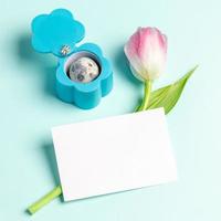 Creative Easter card with jewelry box as flower, quail egg, pink tulip, white note on light blue. photo