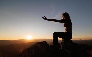 Silhouette of  man rise hand up on top of mountain and sunset sky abstract background. Freedom and travel adventure concept. pray or Praying, remembering God, Copy space . photo