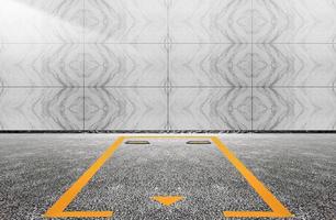 An empty parking space sits between a tiled wall and an asphalt floor photo