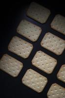 Crunchy bread sprinkled with sugar crumbs and white sesame seeds, arranged on a dark background against studio lighting. photo