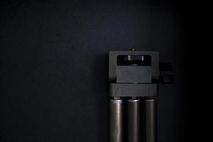 Beautiful old camera tripod on black background in dark room with studio lights photo