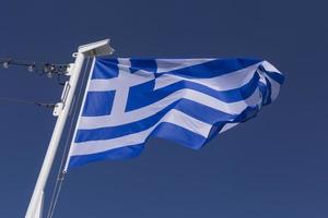 waved flag of Greece hanging on flagpole of ship photo