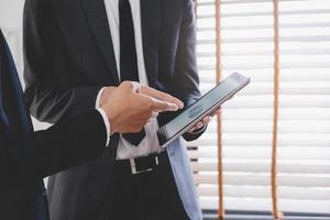 Business meeting, two caucasian, asian group man use tablet brainstorm analyzing on graph data of cost plan or document, paperwork and discussing in board room on table. People working conference room photo