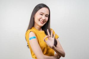 Portrait of pretty, beautiful asian young, teenage attractive after getting, receive anti virus vaccine covid-19. Showing arm on white bandage isolated on white background, copy space. photo