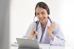 médico o médico vistiendo blanco abrigo, estetoscopio utilizando auriculares, consultante salud por telesalud en línea para Hablando vídeo llamada consulta en tableta. telemedicina por médico para distancia paciente. foto