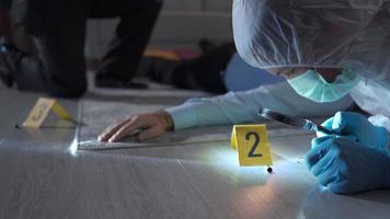 Forensic criminologist man and detective working at the crime scene. The criminologist and the detective man, who examine the evidence at the murder scene, conduct an investigation. video