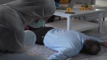 The forensic examiner examines the shell casings near the body. Crime scene. Male forensic expert wearing protective clothing examines the bullet casings at the crime scene and collects evidence. video