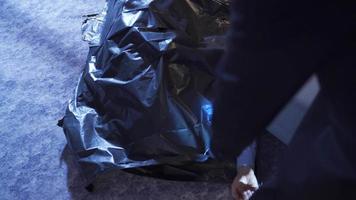 Forensic investigator working at the crime scene. Criminology The police look at the body bag at the crime scene and do analysis.