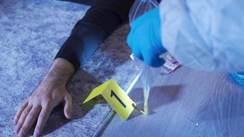 Gathering forensic evidence at the crime scene. A forensic expert in a protective suit examines empty shell casings at the crime scene. video