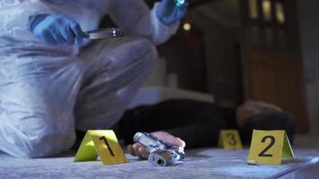 Forensic expert conducting forensic investigation at crime scene. Suicide murder. Crime scene investigator examines gun and bullet casings with a magnifying glass. video