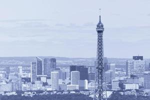 close up of top part of Eiffel tower against La Defense district photo