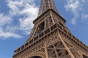 close up o Eiffel tower against blue sky with white clouds photo
