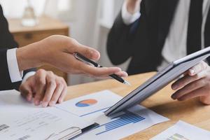Business meeting, two caucasian, asian group man use tablet brainstorm analyzing on graph data of cost plan or document, paperwork and discussing in board room on table. People working conference room photo