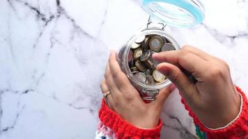 Young man saving coins in a jar white sited video