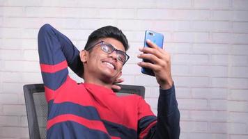 sorridente jovem homem usando dele telefone para faço uma vídeo ligar video