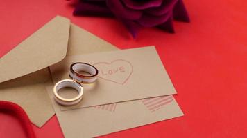 wedding ring, letter and gift box and rose flower on red video