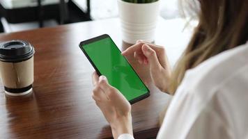 multitarefa às trabalhar, jovem mulher usando telefone enquanto em a trabalho com verde tela video