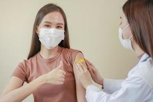 Covid-19,coronavirus hand of young woman nurse,doctor giving syringe vaccine, inject shot to asian arm's patient. Vaccination, immunization or disease prevention against flu or virus pandemic concept. photo