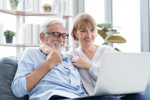 contento mayor pareja, mayor familia, caucásicos maduro, adulto amante y retirado hombre, mujer utilizando ordenador portátil computadora compras en línea, leyendo Noticias en sofá a hogar juntos. marido y esposa estilo de vida. foto