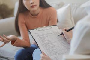 psicología, depresión. triste, sufrimiento asiático joven mujer consultante con psicólogo, psiquiatra mientras paciente asesoramiento mental con médico mujer tomando notas a clínica. alentador, terapia. foto