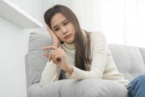 estresado asiático joven pareja, triste mujer pelea en sofá, relación en problema. de la esposa mano participación Boda anillo en decepción y trastornado su marido, cuales mayo dirigir a divorcio. problema de familia foto