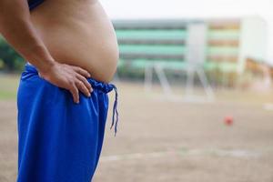 Closeup man shows his big belly, abdomen. Concept, healthcare, health problems, need to exercise or workout for fitness. Overweight or obesity can cause to diseases. photo