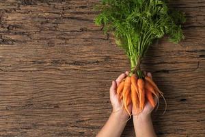 Fresh organic carrots with green leaves on child hand photo