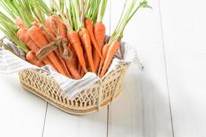 fresh carrot, baby carrot in basket on white wood background photo