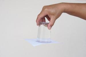 de cerca mano sostener y giro un vaso de agua terminado abajo. cubierto el vaso con papel. concepto, Ciencias experimentar acerca de aire y líquido presión. fácil Ciencias tema actividad, educación. foto