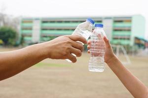 Closeup two hands hold two drinking water bottles outdoor. Concept, Drinking water for health, Healthy lifestyle. Quenching thirst, reduce fatigue, refresh body. photo