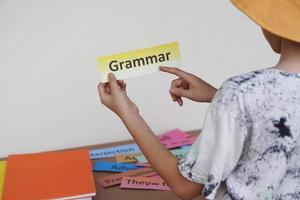 de cerca estudiantes mano sostener Inglés gramática palabra tarjeta. concepto, aprendizaje vocabulario. idioma estudiar. educación. leyendo y memorizando estrategia de aprendizaje proceso para niño. práctica hace Perfecto. foto