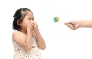 girl with expression of disgust against candy and suffering from toothache photo