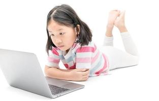 pequeño niña Mira a monitor ordenador portátil aislado foto