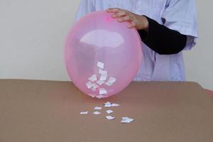 de cerca estudiante hacer Ciencias experimentar acerca de estático electricidad desde rosado globo y piezas de papel. concepto, Ciencias proyecto trabajo actividad. aprendizaje por haciendo. educación. foto