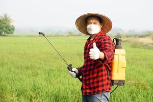 hermoso asiático granjero es pulverización orgánico fertilizante a arrozal campo. concepto utilizando simpático producto con ambiente , agricultura con No productos quimicos usando. la seguridad con usuario y ambiente. foto