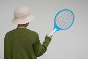 Back view of boy wears hat, holds mosquito electric swatter racket.   Concept, electric device to kill mosquitoes, insects, bugs by swatting to flying insects photo