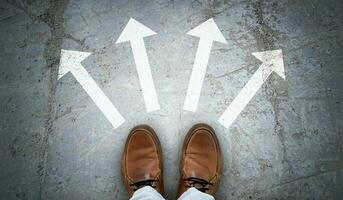 Brown Leather Shoes and Four Chalky Arrows on Asphalt - Choice Concept photo