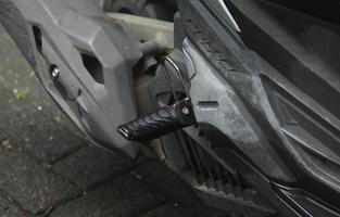 Central Jakarta, Indonesia - March 16th, 2023 - Motorcycles or motorbike parts. Honda transportation in Indonesia. Close up exhaust and driver foot place on the side of the motor bike. photo