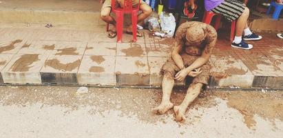 Loei, Thailand - July 6, 2022 Adult or old man stained the mud sitting and asleep at the footpath look like People drunken man in vintage tone. photo