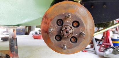 Close up rusty disc brake of car for repair or maintenance at garage. Replacement part of vehicle and fix part photo