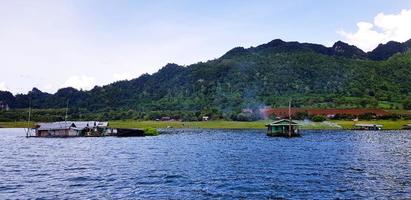 Wooden house or resort for take rest and relaxing are floating on river with beauty of nature. Mountain, Fresh air and Green plant in Srinagarind Dam lake, Kanchanaburi, Thailand. Landmark for trave photo