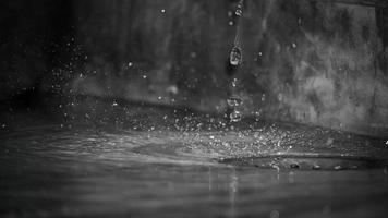 Round rain drops falling on smooth surface of water with grain photo